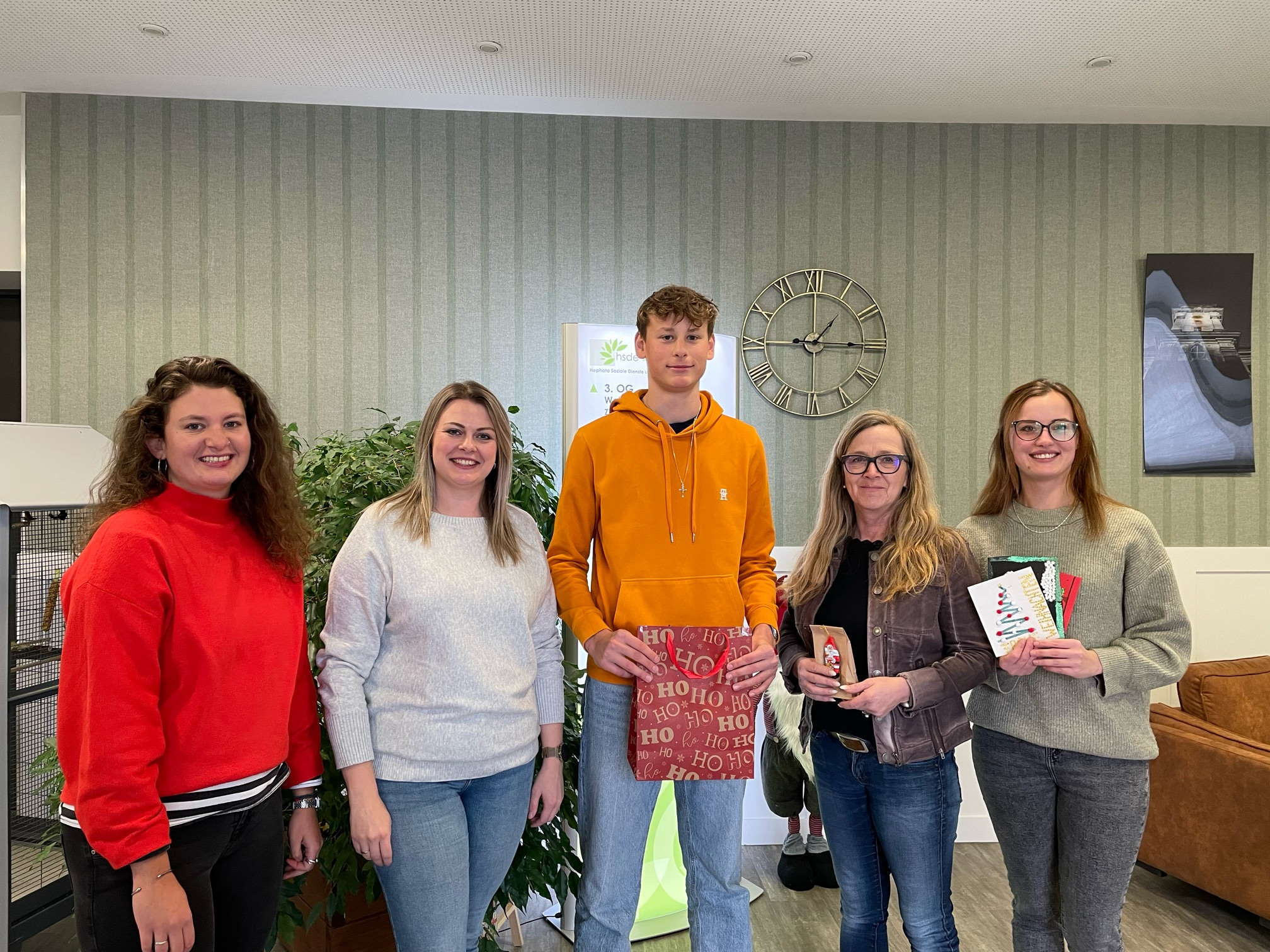 Fünf Menschen haben sich zum Gruppenbild aufgestellt und präsentieren kreative Weihnachtskarten, die Menschen im Seniorenheim zugute kommen sollen. 