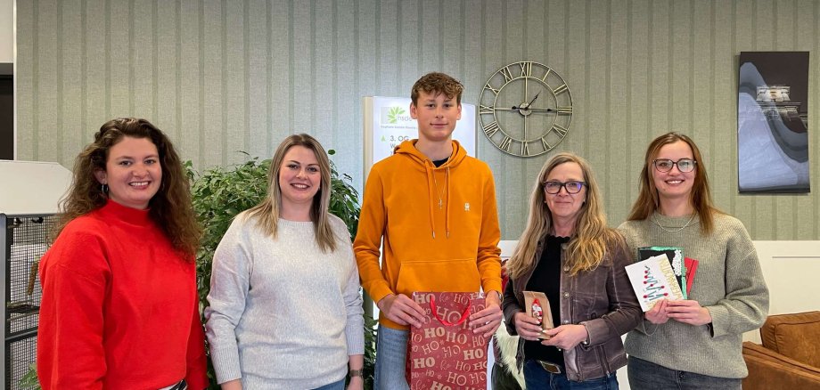 Fünf Menschen haben sich zum Gruppenbild aufgestellt und präsentieren kreative Weihnachtskarten, die Menschen im Seniorenheim zugute kommen sollen. 