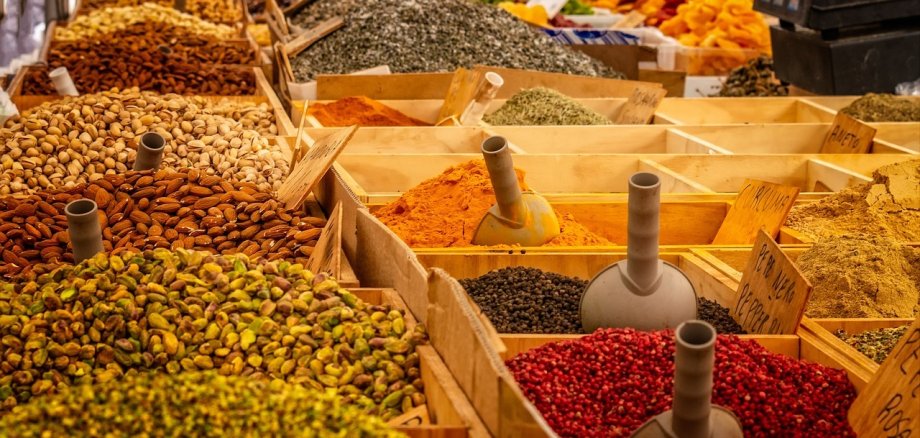 Blick auf einen Marktstand mit vielen bunten Gewürzen in Holzkisten