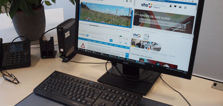 Auf dem Bild ist ein PC-Arbeitsplatz zu sehen. Auf dem Bildschirm ist die Internetseite der vhs zu sehen.