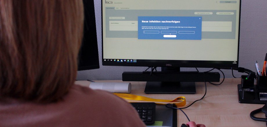 Mitarbeiterin bedient einen PC. Sie führt die Luca-App vor