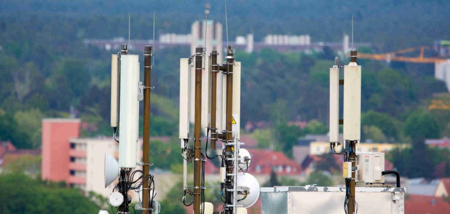 Auf dem Bild sind mehrere Mobilfunkantennen auf einem Dach zu sehen.