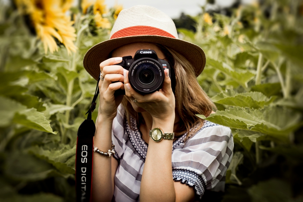 Kreativen Fotospaß verspricht der Workshop des Vogelsberger Jugendamtes, zudem gibt es Infos rund um die digitalen Medien. Eine Frau steht in einem Sonnenblumenfeld und fotografiert.