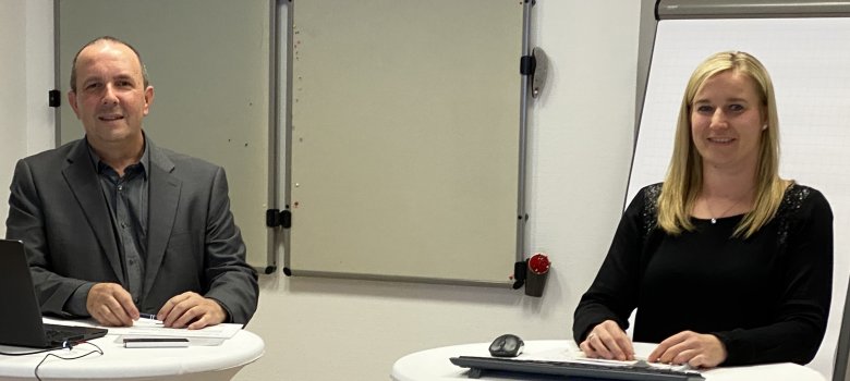 Matthias Steckenreuter und Katharina Barth von der Wirtschaftsförderung des Vogelsbergkreises moderierten die Live-Veranstaltung online aus dem Kreishaus in Lauterbach. Sie stehen an zwei weißen Stehtischen und haben einen Laptop vor sich