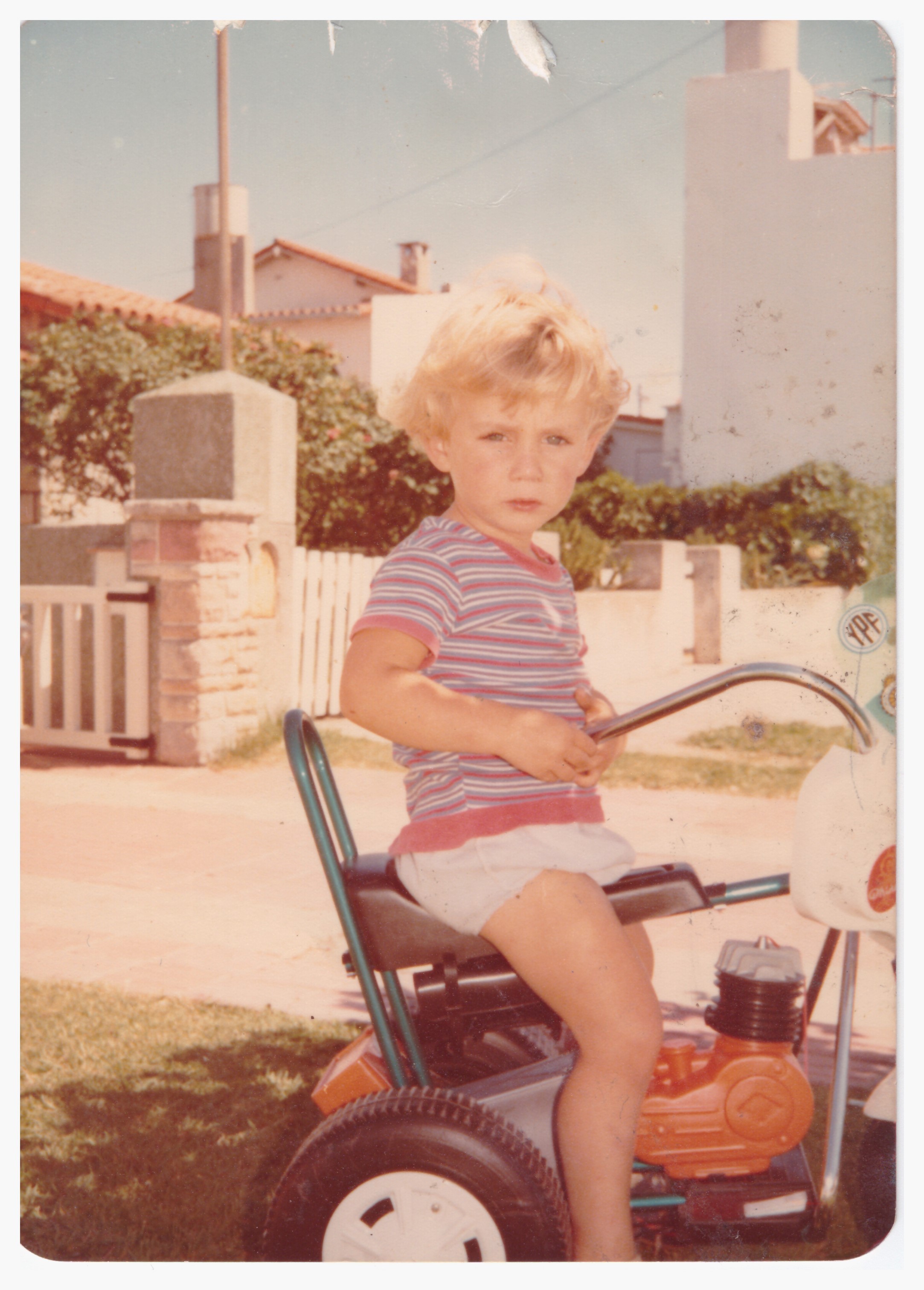 Ein kleiner Junge sitzt auf einem Dreirad. Das Foto ist schon einige Jahrzehnte alt.