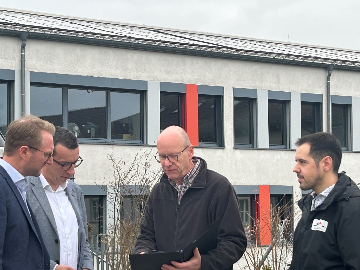 Landrat Dr. Jens Mischak und Erster Kreisbeigeordneter Patrick Krug lassen sich von Jürgen Henke, der den Einbau der Anlage maßgeblich von Seiten des Amtes für Hochbau, Energie und Gebäudewirtschaft begleitet hat, und Klimaschutzmanager Marcel Pfeil, der die gesamte Eine-Millionen-Investitionsoffensive verantwortlich betreut, die technischen Daten der neuen PV-Anlage vorstellen.