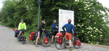 Vier Radfahrer vor einer Hinweistafel