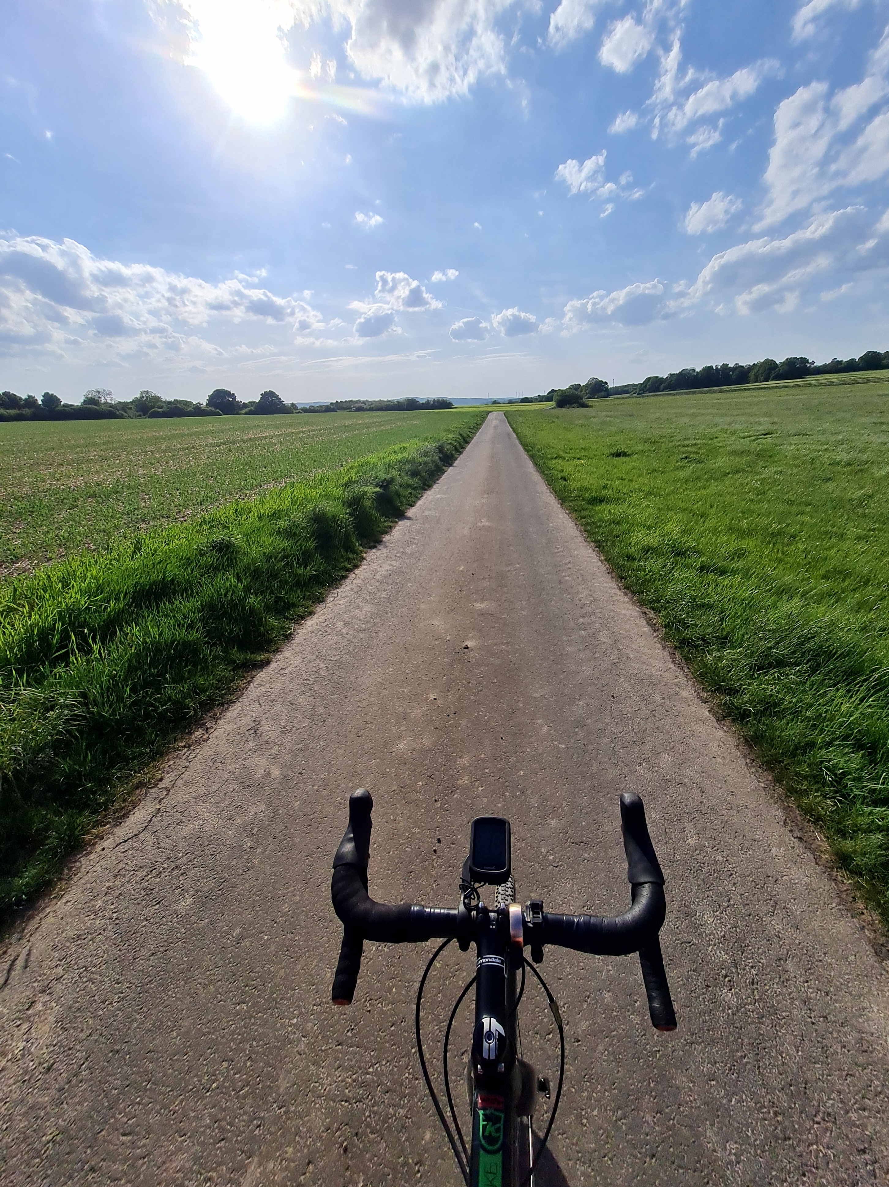 Ein Landschaftsbild, das von einem Fahrrad aufgenommen wurde. im Vordergrund ist der Lenker zu sehen. 
