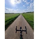 Ein Landschaftsbild, das von einem Fahrrad aufgenommen wurde. im Vordergrund ist der Lenker zu sehen. 