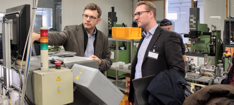 Acti-Med Geschäftsführer Rainer Wiegmann erklärt Wirtschaftsdezernent Dr. Jens Mischak einzelne Maschinen zur Herstellung der Kanülen. 
