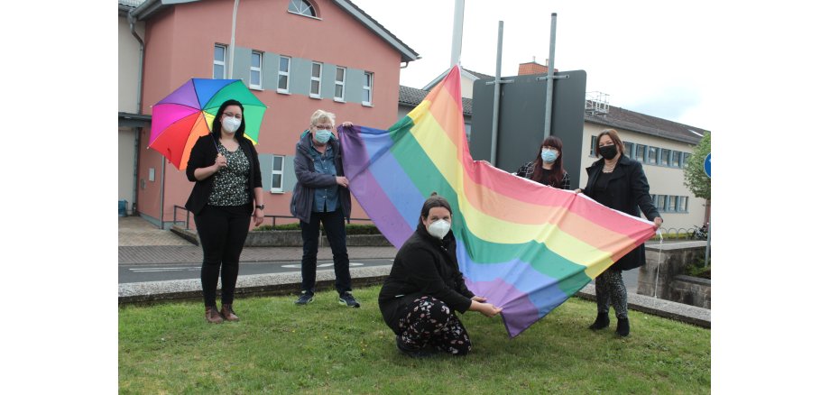 Mitarbeiterinnen hissen die Regenbogen-Fahne vor dem Landratsamt