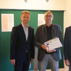 Landrat Dr. Jens Mischak (links), Vorstandsvorsitzender des Vereins Region Vogelsberg, und Edwin Schneider (rechts), Vorsitzender des LEADER-Beirats, überreichen gemeinsam die Weiterleitungsverträge für Mittel aus dem Regionalbudget an Markus Enders vom Schützenverein 1962 Nieder-Ohmen