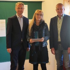 Cornelia Seim-Eichenauer (Mitte) vom TV/VfR Groß-Felda nimmt die Zuwendungsunterlagen für eine überdachte Außenküche von Landrat Dr. Jens Mischak (links), Vorstandsvorsitzender des Vereins Region Vogelsberg, und Edwin Schneider, Vorsitzender des LEADER-Beirats, in Empfang. 