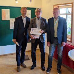 Joachim Legatis (Mitte) vom Verein „Gedenkstätte Speier Angenrod“ nimmt aus den Händen von Landrat Dr. Jens Mischak (links), Vorstandsvorsitzender des Vereins Region Vogelsberg, und Edwin Schneider, Vorsitzender des LEADER-Beirats, den Zuwendungsvertrag entgegen. 
