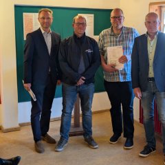 Markus Schlierholz (Zweiter von links) und Markus Lanz vom Evangelischen Posaunenchor Nieder-Ofleiden nehmen die Förderung für die Anschaffung einer Tuba von Landrat Dr. Jens Mischak (links), Vorstandsvorsitzender des Vereins Region Vogelsberg, und Edwin Schneider (rechts), Vorsitzender des LEADER-Beirats, in Empfang. 