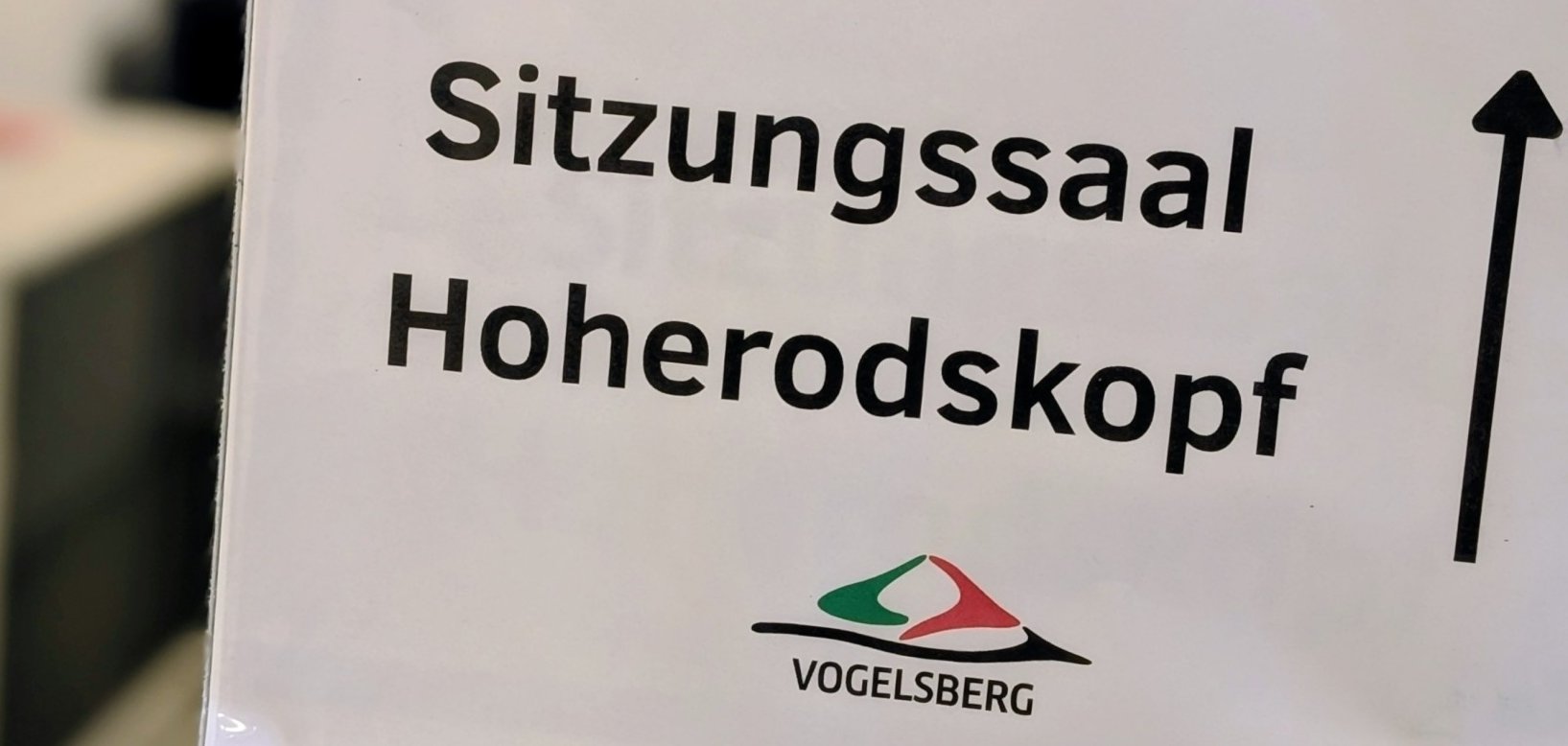 Hinweisschild in einem Flur. Darauf ist "Sitzungssaal Hoherodskopf" zu lesen.