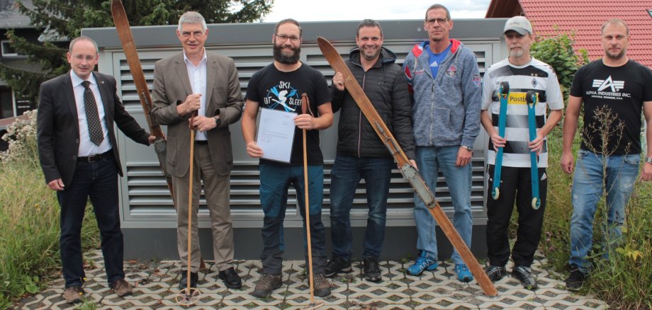 Patrick Rolko, Matthias Papsch, Kai Oechler, Heiko Weck und Florian Appel freuen sich über die Zuwendung in Höhe von 4000 Euro, die Landrat Manfred Görig im Beisein von Bürgermeister Sebastian Stang (von rechts) überreicht. Auch traditionelle Skiausrüstung ist auf dem Bild zu sehen 