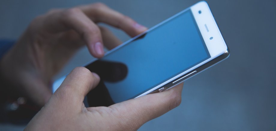 Zwei Hände bedienen ein Smartphone. Auf dem Display ist nichts zu erkennen. 