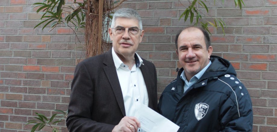 Landrat Manfred Görig überreicht Carsten Weitzel, dem Vorsitzenden des Jugendfördervereins Alsfeld, eine Spende der OVAG für den Spiel- und Trainingsbetrieb.