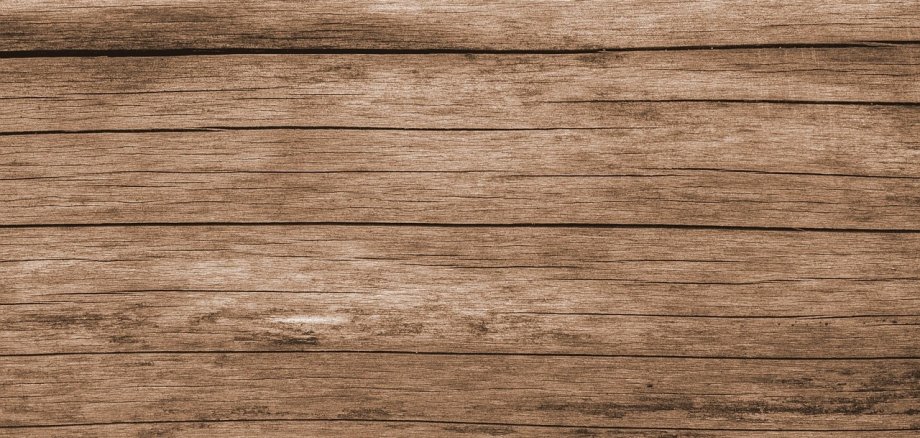 Dunkelbraune Holzbretter, die zu einem Fußboden verarbeitet sind. 