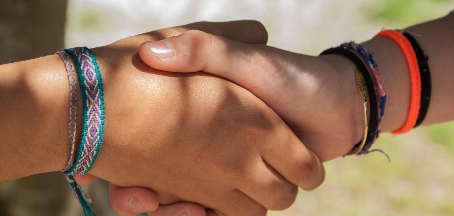 Zwei Kinder geben sich die Hand. Es sind nur die beiden Hände zu sehen.