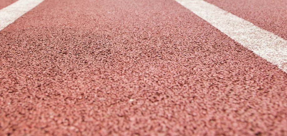 Nahaufnahme einer roten Kunststoffbahn auf einem Sportplatz
