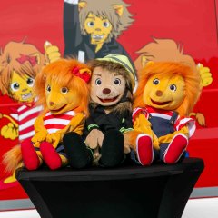 Die drei Maskottchen der Brandschutzerziehung. Zwei Plüsch-Löwen und ein -Feuerwehrmann