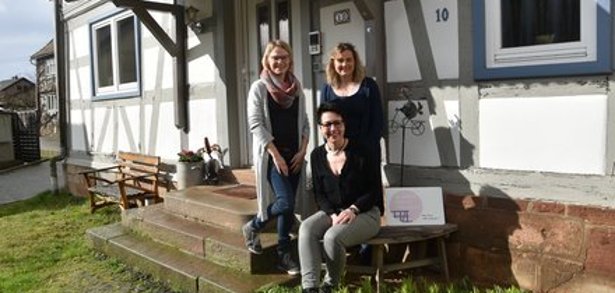 Hier sind Radler herzlich willkommen: Die Ferienwohnung „#uebernachtenswert“ von Sabine Kneipp (sitzend) in Birstein wurde mit dem Siegel „bett+bike“ ausgezeichnet. Ilka Schacht (li.) von der Region Vogelsberg Touristik GmbH und Silvia Bittner (re.) von der Gemeinde Birstein kommen zum Gratulieren.