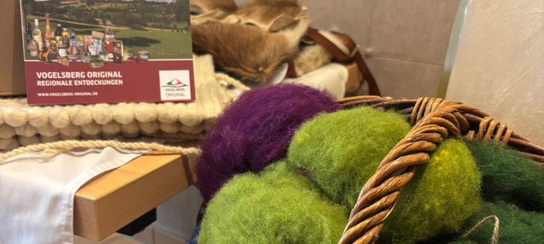 Bunte Wolle in einem Korb und eine Broschüre im Hintergrund