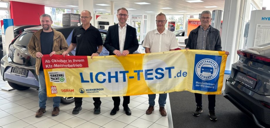 Landrat und Straßenverkehrsdezernent Dr. Jens Mischak (Mitte), macht gemeinsam mit Sebastian Volp (von links), Vorstandsmitglied der Innung des Kfz-Gewerbes Oberhessen, Kundendienstleiter Mario Krug und Geschäftsführer Ralf Geissler vom Auto-Center-Alsfeld AH GmbH, sowie Hubert Röhrig, Schriftführer der Verkehrswacht Vogelsbergkreis, auf den „Licht-Sicht-Test 2026“ aufmerksam. In teilnehmenden Innungswerkstätten können Autofahrer ab Oktober kostenfrei ihre Beleuchtung inspizieren lassen.