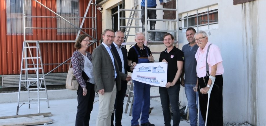 Firma Ludwig in Ulrichstein schafft Platz für Büros und Ausstellungsflächen. Für ein Gruppenbild haben sich die beteiligten an der Baustelle aufgestellt. Andrea Ortstadt (Wirtschaftsförderung Vogelsbergkreis), Wirtschaftsdezernent Dr. Jens Mischak und Bürgermeister Edwin Schneider (v. li.) besuchten den Betrieb. Roland Ludwig und Sohn Fabian halten den Bauplan, rechts daneben stehen Bodo Stein (Heizungsbaumeister) und der Seniorchef Reinhold Ludwig. 