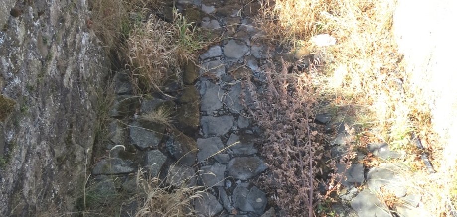 Trockengefallene Bäche im Vogelsberg – hier der Gilgbach in Bobenhausen II – machen eine Aufhebung des Entnahmeverbots von Wasser unmöglich. Auf dem Foto ist das ausgetrocknete mit BAsaltsteinen befestigte Bachbett zu sehen.