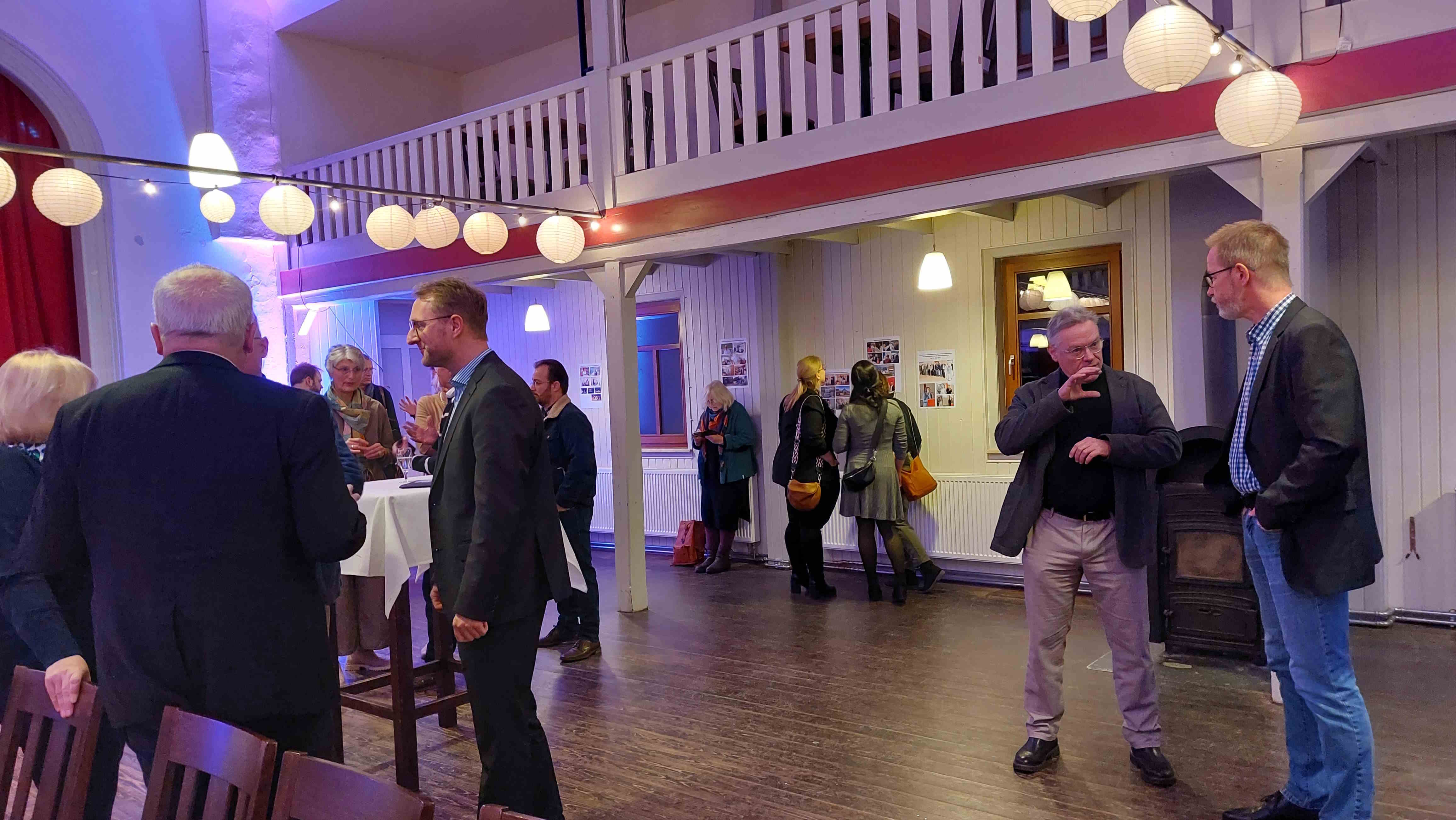 Menschen stehen in Grüppchen in einem Saal und sprechen miteinander