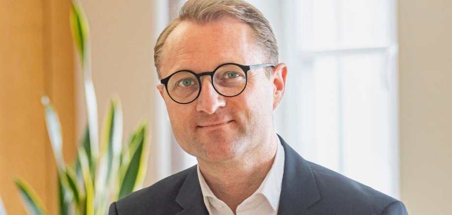 Porträtfoto von Dr. Jens Mischak. Er sitzt auf seinem Schreibtisch