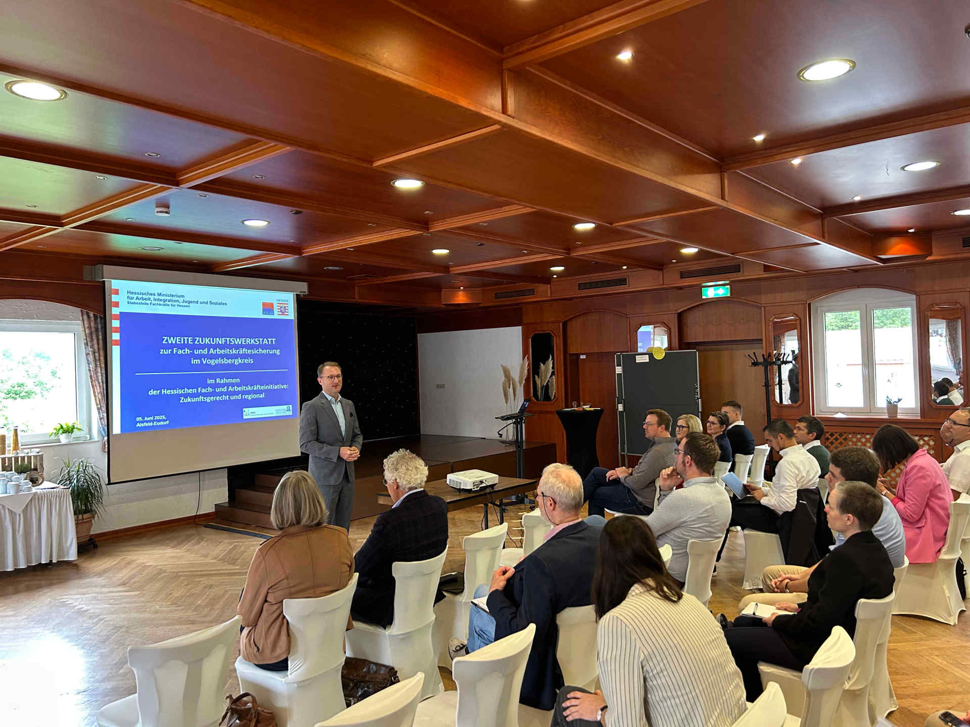 Landrat Dr. Mischak spricht in einem Konferenzsaal vor rund 50 Personen
