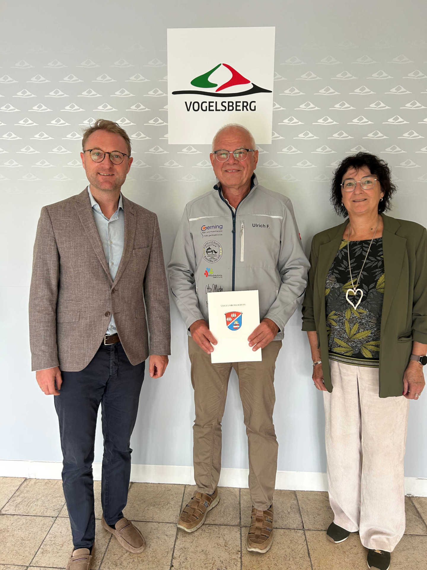 Landrat Dr. Jens Mischak und Anke Koch, zuständig für die Sportförderung in der Vogelsberger Kreisverwaltung, überreichen Ulrich Fritzges den Bewilligungsbescheid.