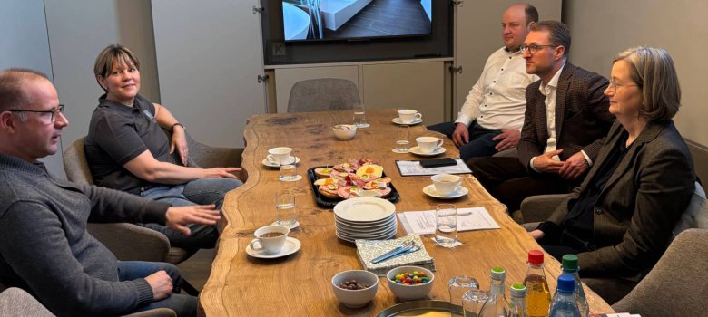 Fünf Personen sitzen an einem Besprechungstisch und unterhalten sich. 