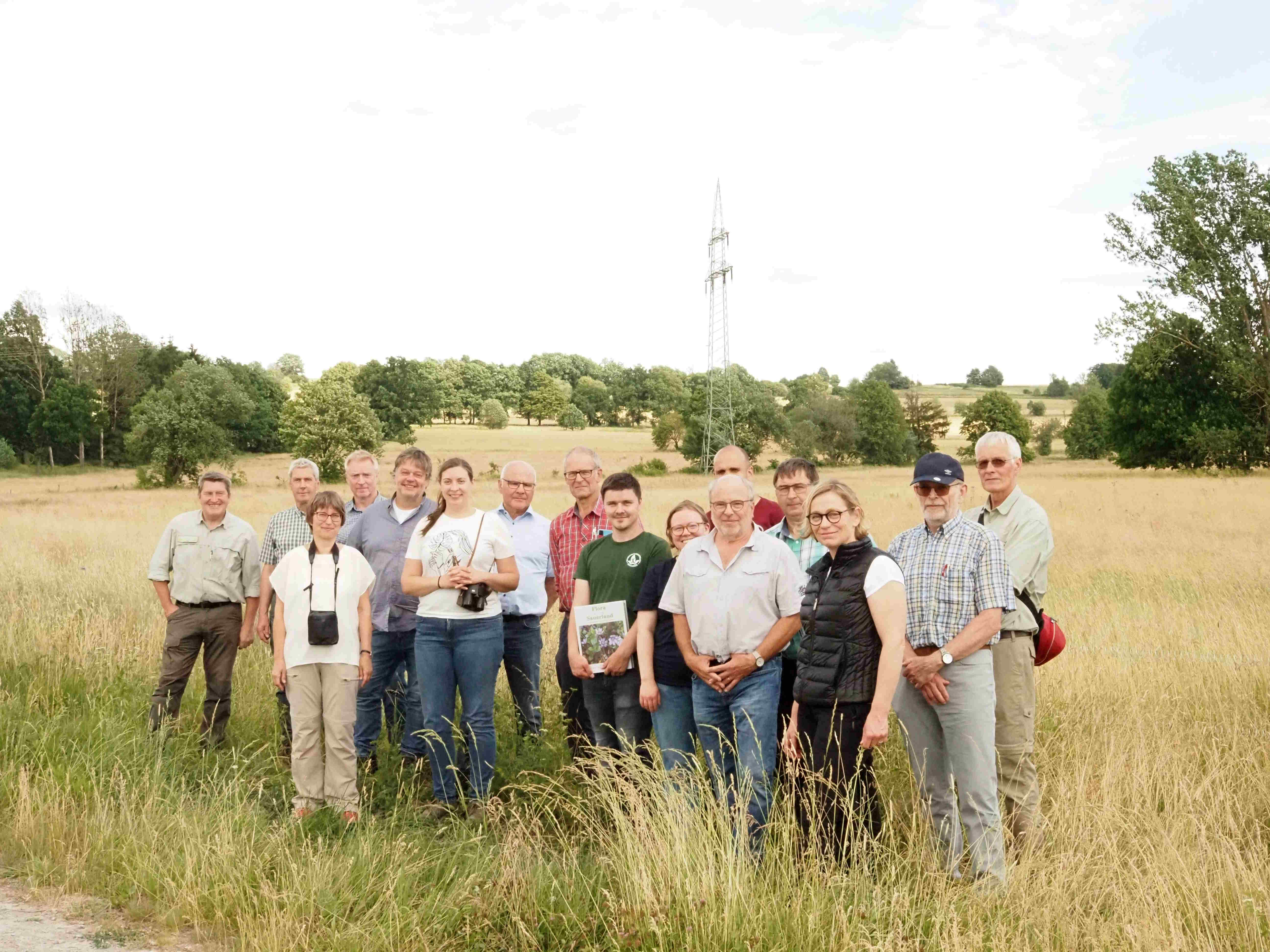 Eine Gruppe Menschen hat sich auf einer Wiese zum Gruppenfoto aufgestellt. 