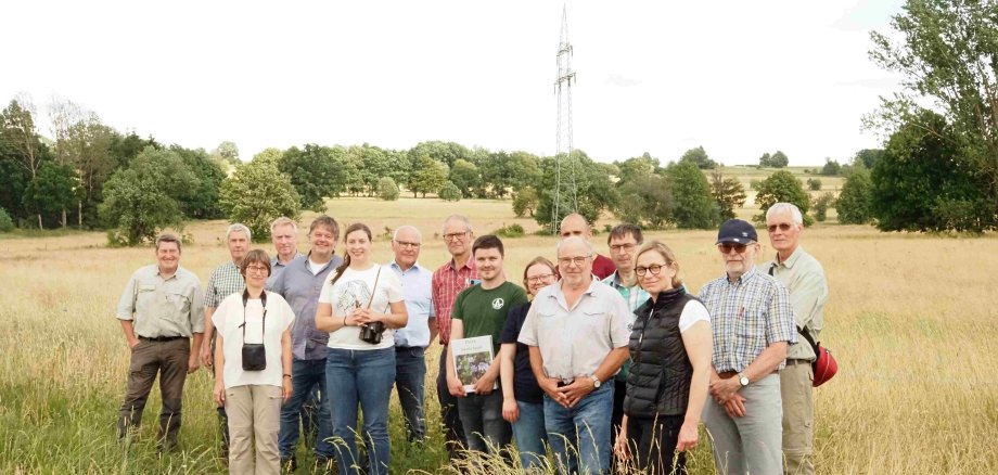 Eine Gruppe Menschen hat sich auf einer Wiese zum Gruppenfoto aufgestellt. 