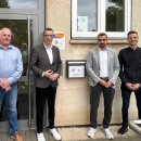 fünf Menschen haben sich für ein Gruppenfoto aufgestellt und lächeln in die Kamera.
