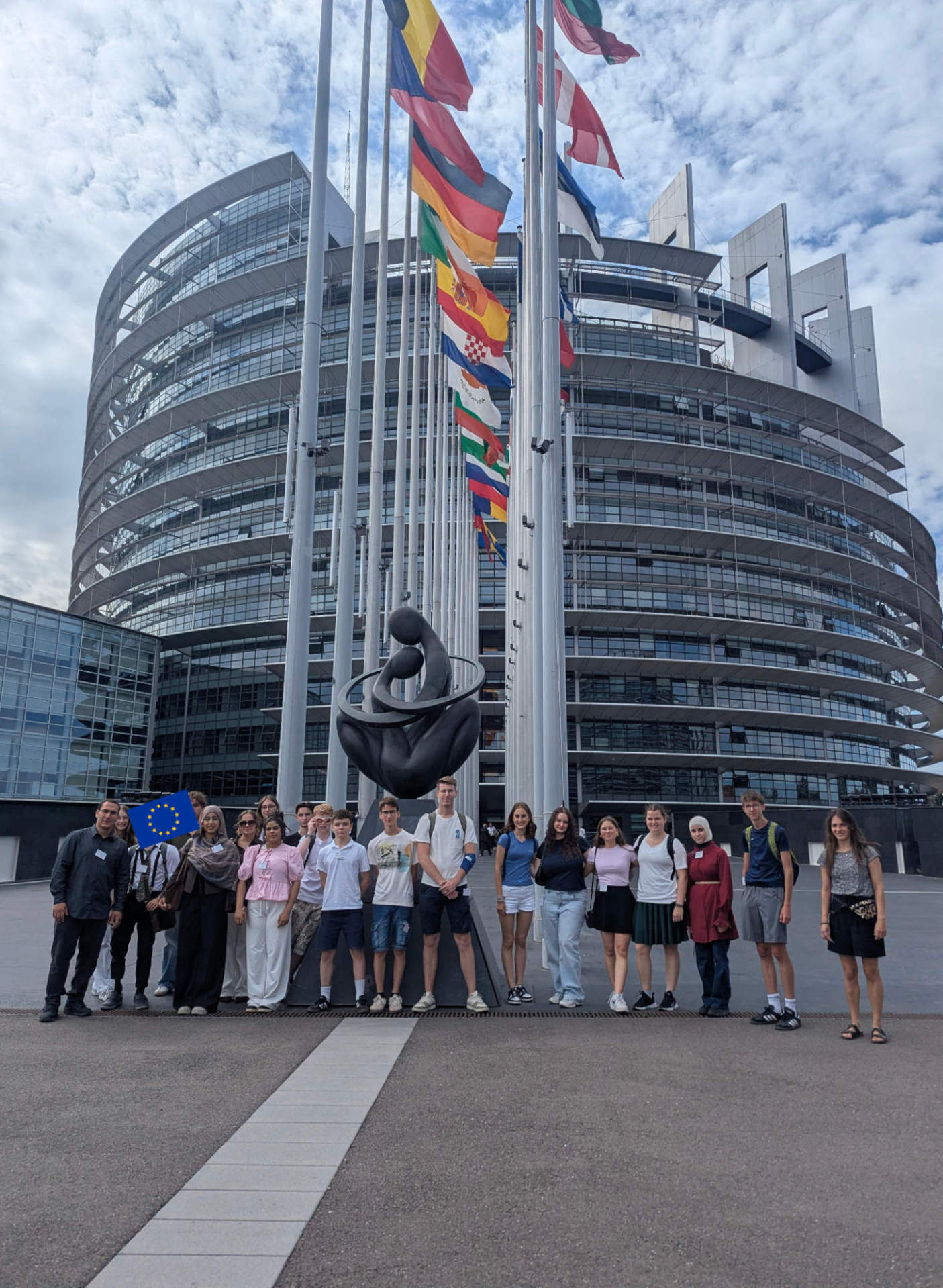  Das Fazit fällt eindeutig aus: Die Bildungsreise „EU und DU“ war ein voller Erfolg. Eine Gruppe Jugendlicher hat sich in Straßburg vor einem EU-Gebäude für ein Gruppenbild aufgestellt. Im Hintergrund sind Fahnenmasten zu sehen.