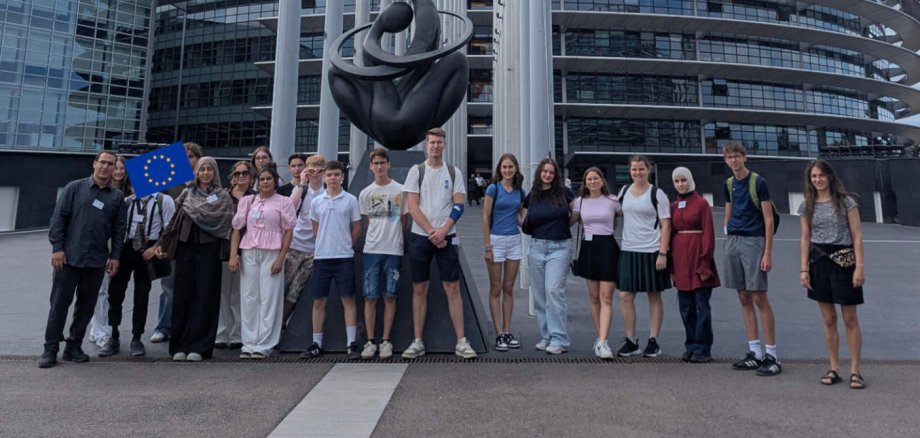 Das Fazit fällt eindeutig aus: Die Bildungsreise „EU und DU“ war ein voller Erfolg. Eine Gruppe Jugendlicher hat sich in Straßburg vor einem EU-Gebäude für ein Gruppenbild aufgestellt. Im Hintergrund sind Fahnenmasten zu sehen.
