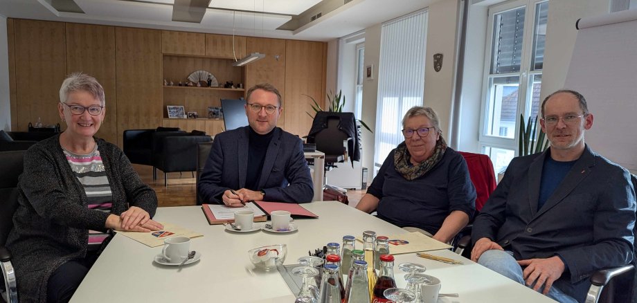 Vier Menschen sitzen an einem Konferenztisch und schauen in die Kamera. Sie haben gerade einen Vertrag unterzeichnet, der die Sozialarbeit in Schulen im Vogelsbergkreis regelt. 