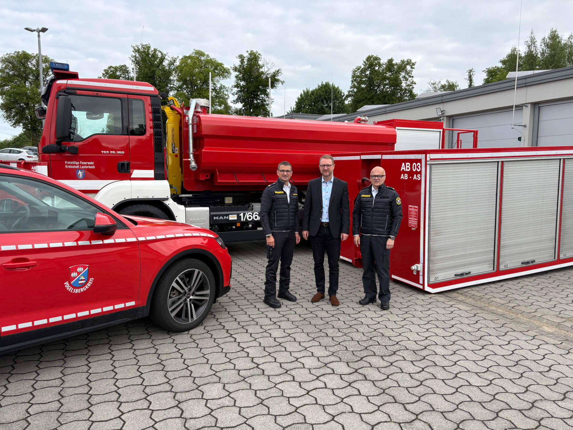 Bei der Lauterbacher Feuerwehr bereits im Einsatz erprobt: Wechsellader sollen zukünftig kreisweit zum Einsatz kommen. Landrat Dr. Jens Mischak (Mitte), Kreisbrandinspektor Marcell Büttner (links) und Kreisbrandmeister Tony Michelis präsentieren am Standort der Feuerwehr Lauterbach-Mitte, wie Wechsellader-Fahrzeug und Abrollbehälter aussehen.