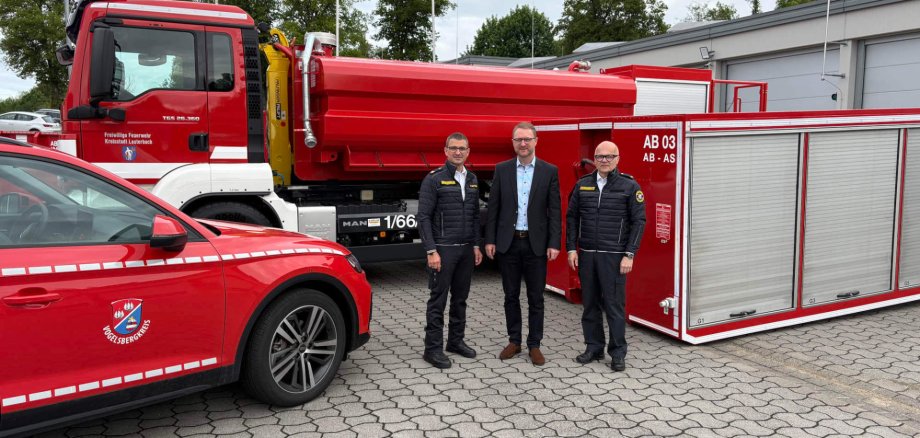 Bei der Lauterbacher Feuerwehr bereits im Einsatz erprobt: Wechsellader sollen zukünftig kreisweit zum Einsatz kommen. Landrat Dr. Jens Mischak (Mitte), Kreisbrandinspektor Marcell Büttner (links) und Kreisbrandmeister Tony Michelis präsentieren am Standort der Feuerwehr Lauterbach-Mitte, wie Wechsellader-Fahrzeug und Abrollbehälter aussehen.