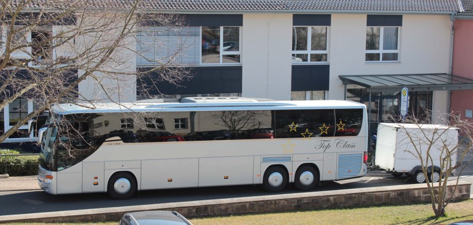 Ein großer beiger Reisebus mit Anhänger steht vor dem Eingang zu einem Schulgebäude. Mit ihm sind Flüchtlinge aus der Ukraine in den Vogelsbergkreis gekommen. 
