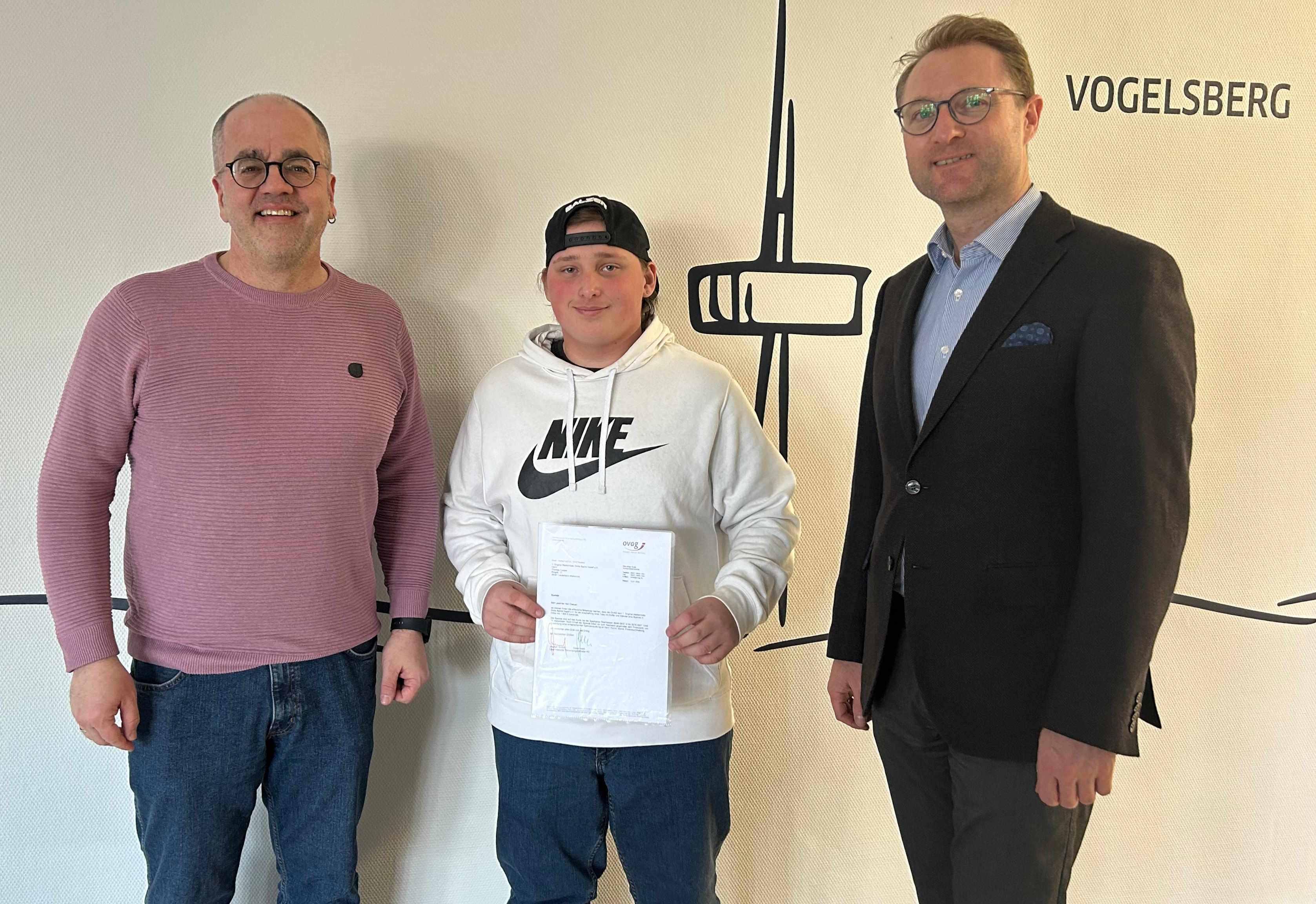 Landrat Dr. Mischak (rechts) übergibt eine Spende der OVAG an Thomas Caspar (links), vom Vorstand der 1. Original Wallenröder Dicke Backe Kapell‘, und Nachwuchs-Tubist Nico. Die Spende in Höhe von 1.500 Euro unterstützt die Anschaffung einer vereinseigenen Tuba mit zusätzlicher Ausstattung.