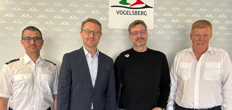 Landrat Dr. Jens Mischak, Kreisbrandinspektor Marcell Büttner und Jürgen Schad, stellvertretender Leiter des Amtes für Gefahrenabwehr, begrüßen mit Daniel Pree (Zweiter von rechts) einen weiteren Ärztlichen Leiter im Rettungsdienst.