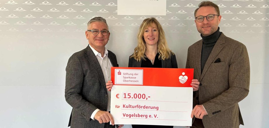 Bis zu 15.000 Euro der Kosten für den Vulkansommer 2025 übernimmt die Stiftung der Sparkasse Oberhessen: Landrat Dr. Jens Mischak (rechts), stv. Vorsitzender der Stiftung der Sparkasse Oberhessen und Sparkassendirektor Frank Dehnke (links) überreichen die Förderzusage an Carolin Henningsen, Kulturförderung Vogelsberg e. V. Die Defizitgarantie sichert das kulturelle Sommerfestival in der Region ab – zur Freude aller Beteiligten