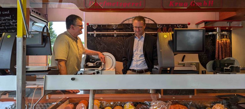Landrat und Wirtschaftsdezernent Dr. Jens Mischak (rechts) und Kai Döring, Metzgermeister und Inhaber der Dorfmetzgerei Krug, in einem Verkaufswagen, der auf Wochenmärkten im Rhein-Main-Gebiet eingesetzt wird.